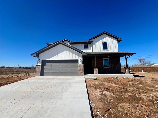 view of front of home with an attached garage, concrete driveway, board and batten siding, and brick siding