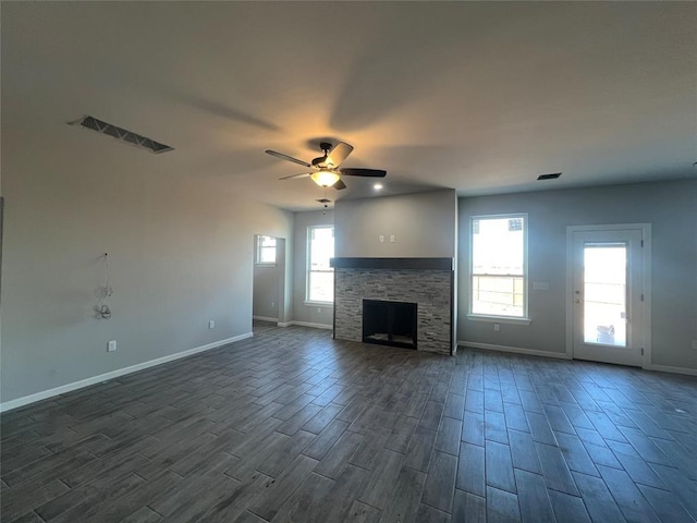 unfurnished living room with baseboards, visible vents, a ceiling fan, dark wood-type flooring, and a fireplace