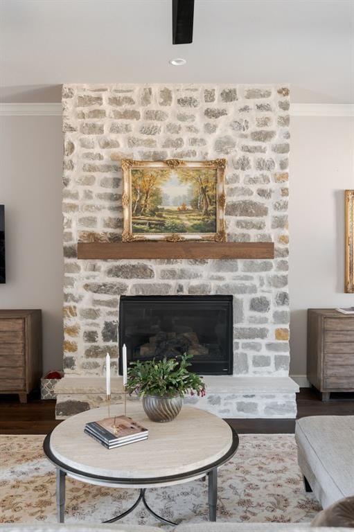 living room featuring a fireplace, hardwood / wood-style flooring, and crown molding