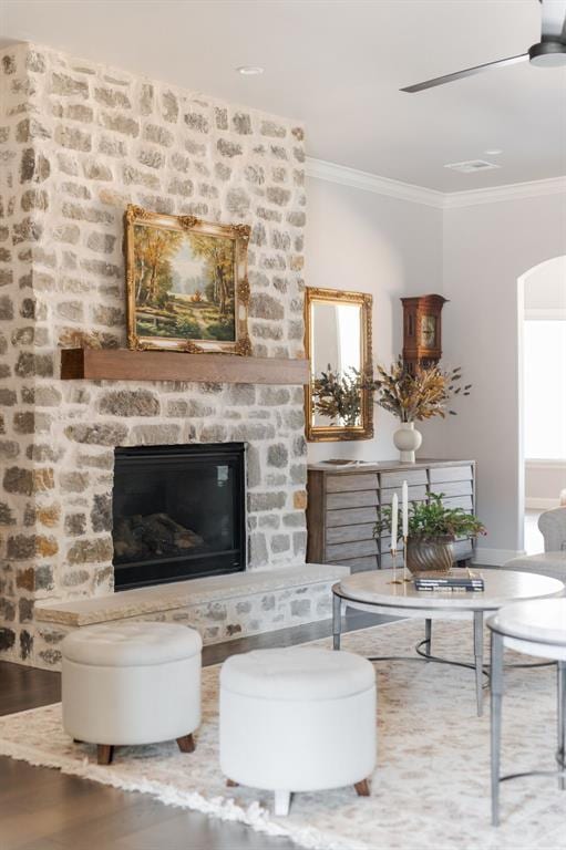 living room with ceiling fan, crown molding, a fireplace, and wood-type flooring