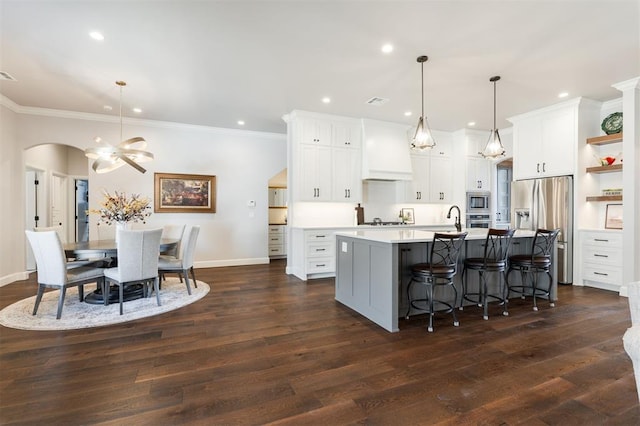 kitchen featuring hanging light fixtures, appliances with stainless steel finishes, white cabinetry, dark hardwood / wood-style floors, and an island with sink