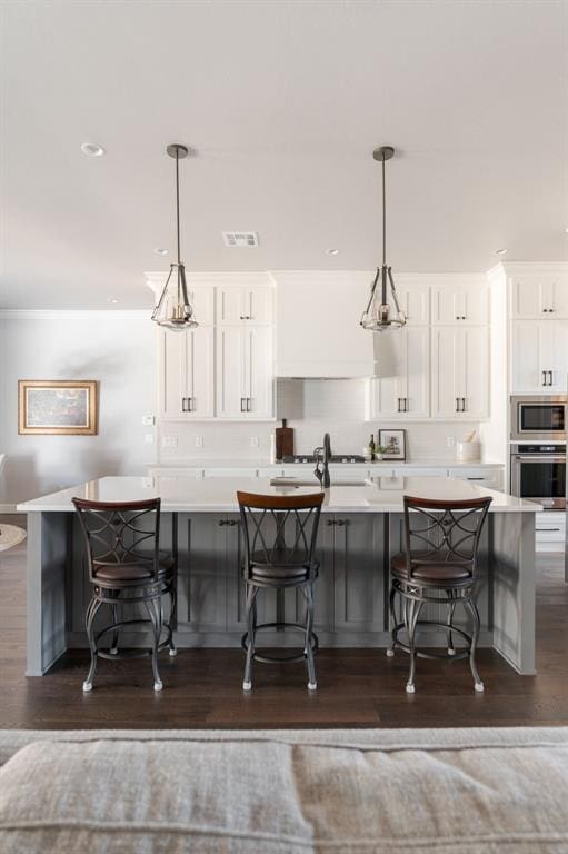 kitchen featuring white cabinetry, a breakfast bar area, hanging light fixtures, and stainless steel appliances