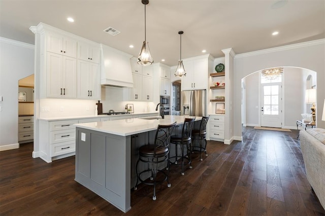 kitchen featuring white cabinetry, an island with sink, custom exhaust hood, and appliances with stainless steel finishes