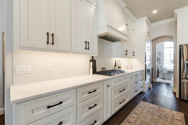 kitchen with custom exhaust hood, stainless steel gas cooktop, tasteful backsplash, white cabinetry, and dark hardwood / wood-style flooring