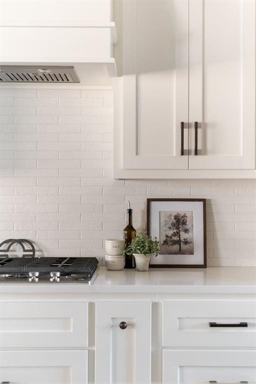 interior details with white cabinetry, decorative backsplash, and stainless steel gas cooktop