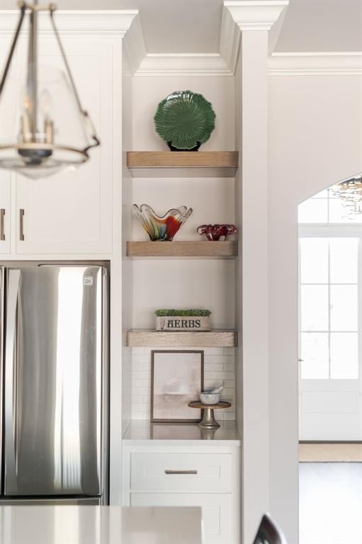 bar with crown molding, white cabinetry, and stainless steel refrigerator