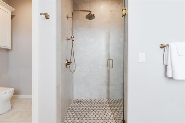 bathroom featuring a shower with shower door, toilet, and tile patterned flooring