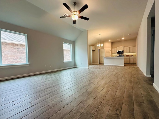 unfurnished living room with baseboards, lofted ceiling, ceiling fan with notable chandelier, wood finished floors, and a wall mounted AC