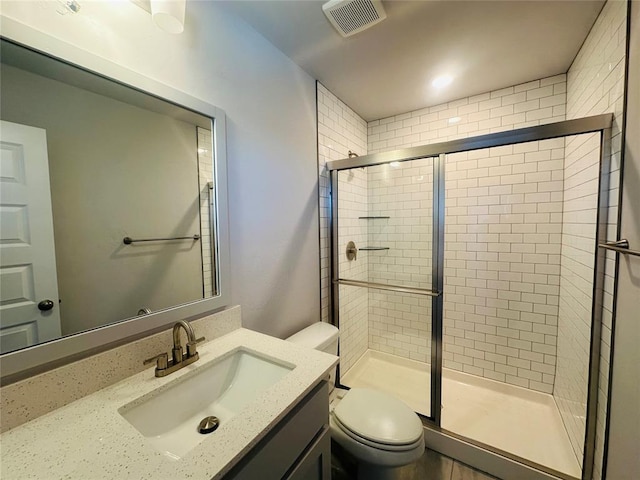 bathroom with visible vents, vanity, toilet, and a shower stall