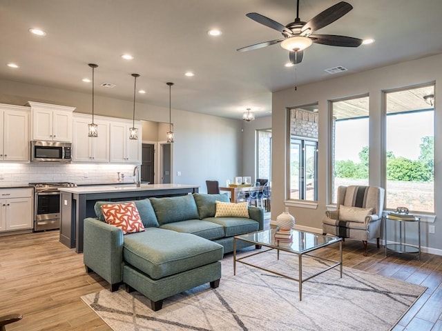 living room featuring sink, ceiling fan, and light hardwood / wood-style flooring