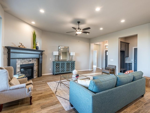 living room with ceiling fan and a stone fireplace