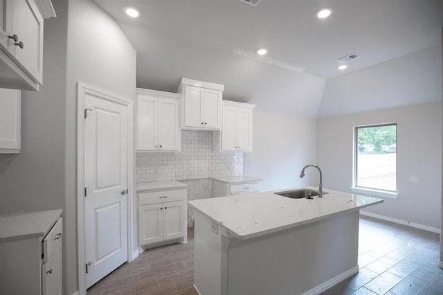 3120 Warwick Way, Moore, OK 73160 - kitchen featuring decorative backsplash, lofted ceiling, a center island with sink, white cabinetry, and wood finished floors