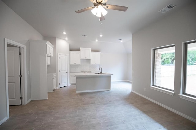 3120 Warwick Way, Moore, OK 73160 - kitchen featuring a ceiling fan, white cabinets, decorative backsplash, a center island with sink, and light countertops