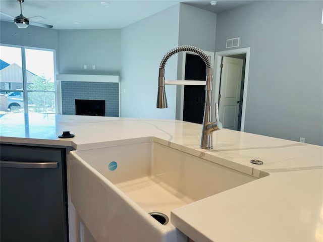 interior space featuring ceiling fan, a tiled fireplace, and sink