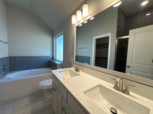 full bathroom with vaulted ceiling, separate shower and tub, vanity, and toilet