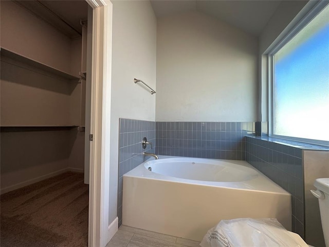 bathroom featuring a tub to relax in, vaulted ceiling, and toilet