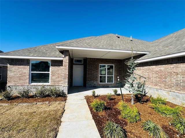 property entrance with brick siding and roof with shingles