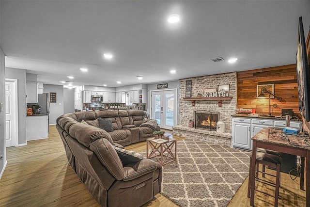 living room with hardwood / wood-style flooring, french doors, wooden walls, and a fireplace