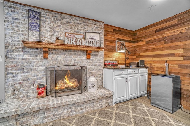 living room featuring a brick fireplace, wood walls, and light hardwood / wood-style flooring