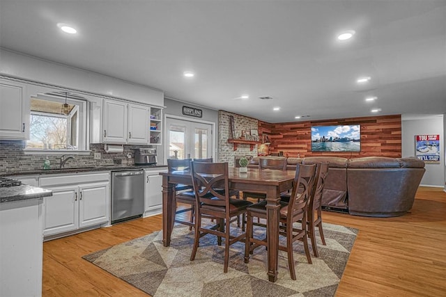 dining room with sink, wood walls, french doors, and light wood-type flooring