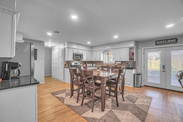 dining area with light hardwood / wood-style floors, a wealth of natural light, and french doors