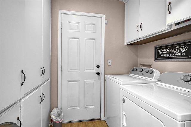 laundry area with washing machine and dryer, light wood-type flooring, and cabinets