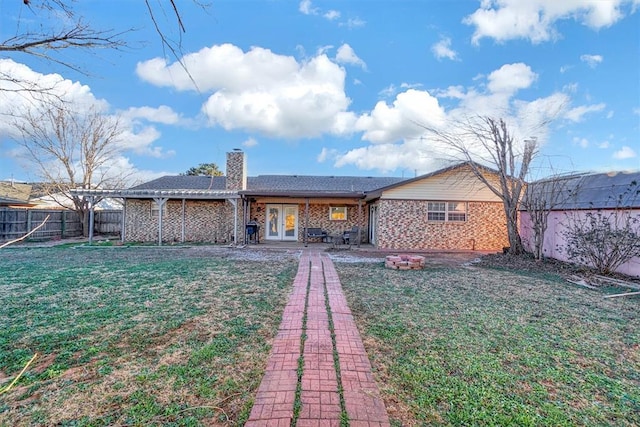 rear view of house featuring a fire pit, a patio, a yard, and french doors