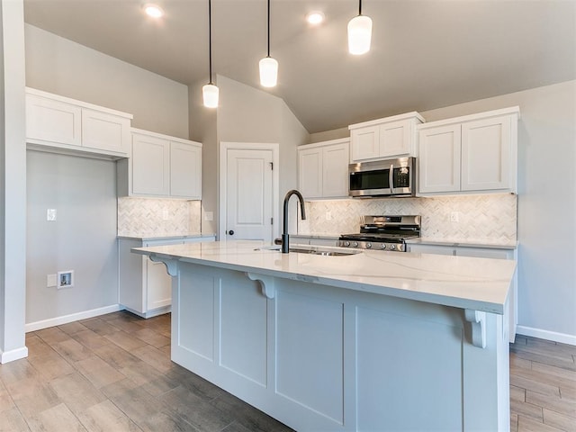 kitchen with appliances with stainless steel finishes, a kitchen island with sink, pendant lighting, white cabinets, and sink