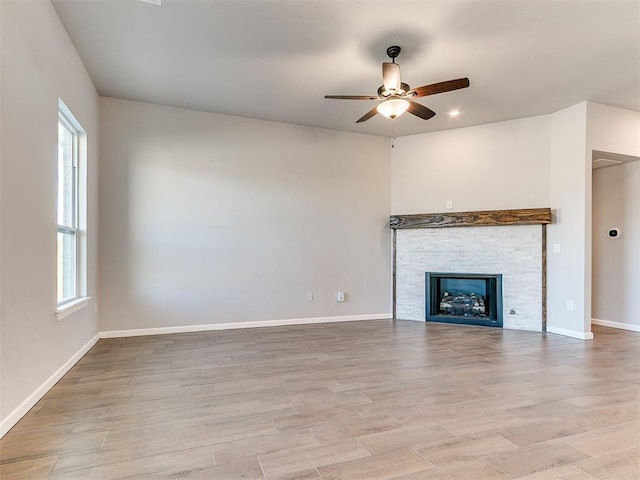 unfurnished living room with ceiling fan, a healthy amount of sunlight, and a stone fireplace