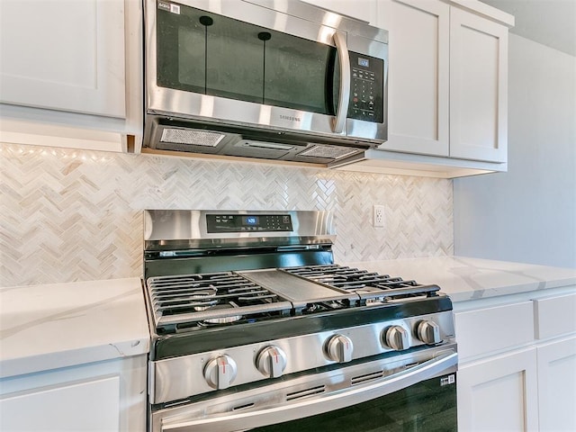 kitchen featuring light stone countertops, white cabinets, appliances with stainless steel finishes, and tasteful backsplash