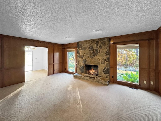 unfurnished living room with a fireplace, light carpet, and a textured ceiling