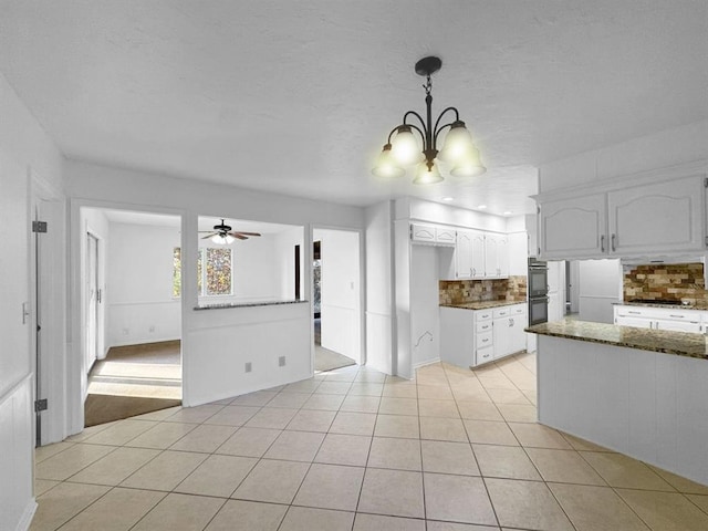 kitchen featuring light tile patterned flooring, decorative light fixtures, tasteful backsplash, dark stone countertops, and white cabinets