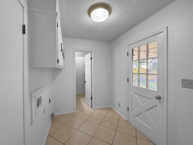 laundry area with light tile patterned floors, hookup for a washing machine, cabinets, a textured ceiling, and hookup for an electric dryer