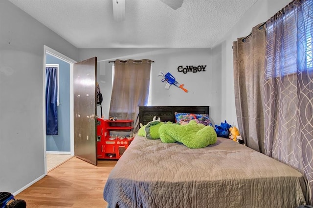 bedroom with ceiling fan, hardwood / wood-style floors, and a textured ceiling