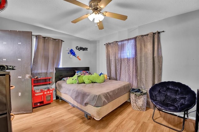 bedroom with ceiling fan, a textured ceiling, and hardwood / wood-style flooring