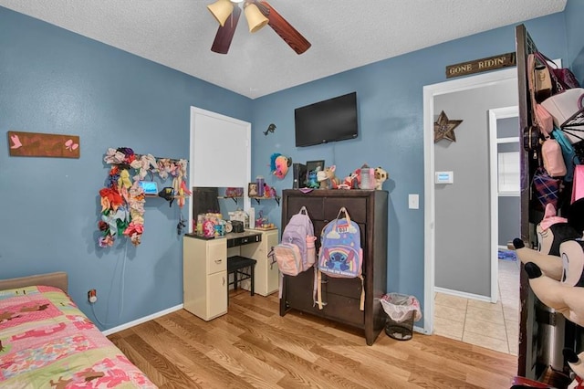 bedroom with light wood-type flooring, ceiling fan, and a textured ceiling