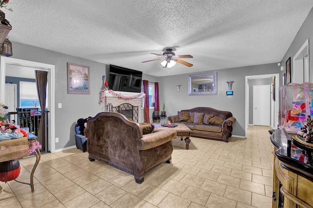 tiled living room featuring ceiling fan, a fireplace, and a textured ceiling