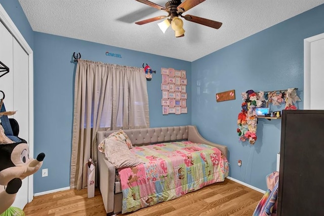 bedroom featuring ceiling fan, a textured ceiling, a closet, and light hardwood / wood-style flooring