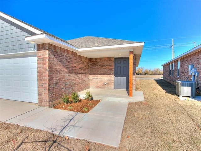 entrance to property featuring a garage and central AC unit