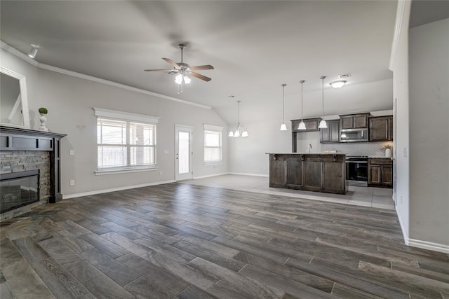 unfurnished living room featuring dark wood-type flooring, a stone fireplace, ceiling fan with notable chandelier, and crown molding