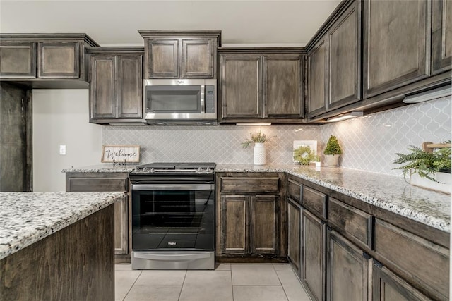 kitchen with light stone counters, light tile patterned flooring, dark brown cabinetry, and appliances with stainless steel finishes