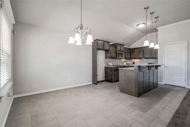 kitchen featuring decorative light fixtures, dark brown cabinets, a kitchen breakfast bar, and an island with sink