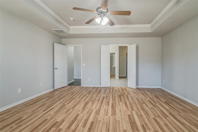 unfurnished bedroom with a tray ceiling, ornamental molding, ceiling fan, and light wood-type flooring