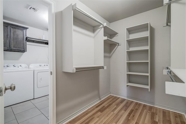 spacious closet featuring washing machine and clothes dryer and light wood-type flooring