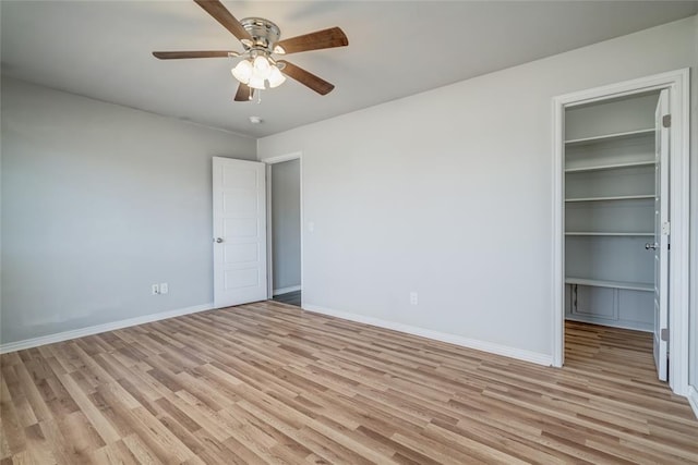 unfurnished bedroom featuring a closet, a walk in closet, and light hardwood / wood-style flooring