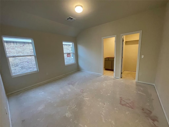 unfurnished bedroom featuring vaulted ceiling, a closet, and a walk in closet