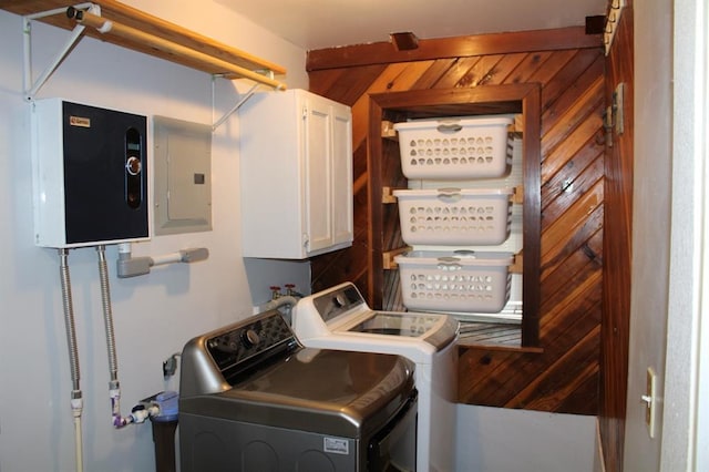 laundry area featuring washer and clothes dryer, electric panel, cabinets, and wooden walls