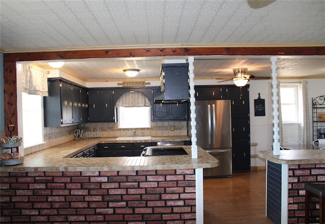 kitchen with kitchen peninsula, sink, backsplash, and stainless steel fridge