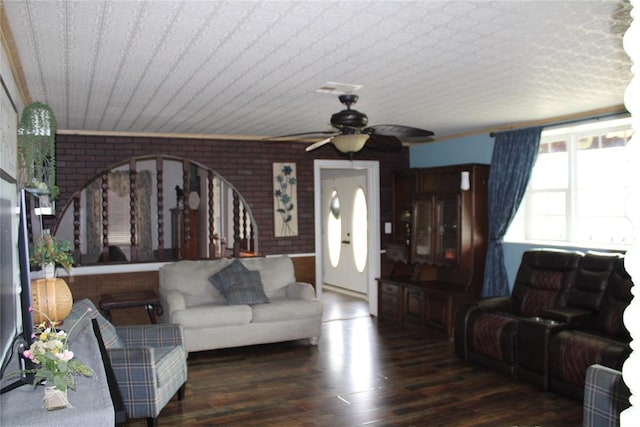 living room with dark wood-type flooring, brick wall, and ceiling fan