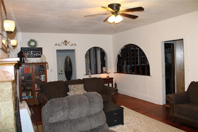 living room with ceiling fan with notable chandelier and dark hardwood / wood-style floors